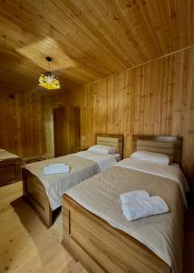 two beds in a room with wooden walls at Ord INN in Oni