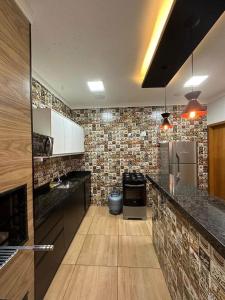 a kitchen with black counter tops and a brick wall at Área de Lazer DAY USE - Chácara do Danilo in Maringá