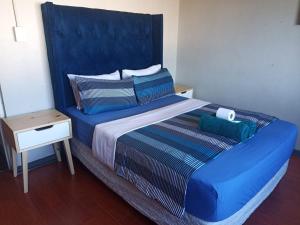 a large bed with a blue headboard in a room at SkyWags Guest House in Bloemfontein