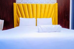 a bed with a yellow headboard and white pillows at SkyWags Guest House in Bloemfontein