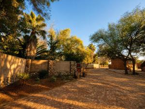 a brick road with a fence and a palm tree at Lake Cabin in Olifantshoek