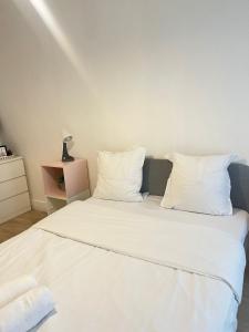 a white bed with white sheets and pillows at Appartement familial RDC in Boulogne-Billancourt