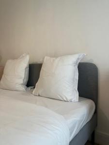 a bed with two white pillows on top of it at Appartement familial RDC in Boulogne-Billancourt