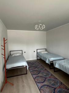 ein Zimmer mit zwei Betten und einem Teppich in der Unterkunft KölToo in Barskoon
