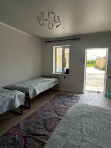 Ein Zimmer mit zwei Betten, einem Fenster und einem Teppich in der Unterkunft KölToo in Barskoon