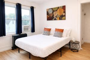 a bedroom with a large white bed with two windows at Downtown High Falls Studio Apt, Kitchen, TV in Rochester
