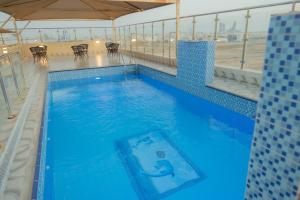 a large blue swimming pool with tables and chairs at Qasr Arin Aprtments For Serviced Apartments شقق قصر ارين للشقق المخدومة in Jeddah