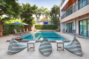 a swimming pool with two lounge chairs and a building at The BELL in Nai Yang Beach