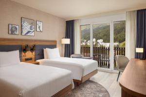 a hotel room with two beds and a balcony at Hilton Garden Inn Davos in Davos +151 photos