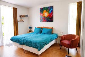 a bedroom with a bed and a chair and a painting at Luxury Suites Oosterwold in Almere