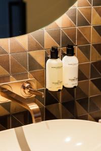 Zwei Seifenflaschen stehen auf einem Waschbecken im Badezimmer. in der Unterkunft Designhotel Beila in Bilzen + 19 Fotos