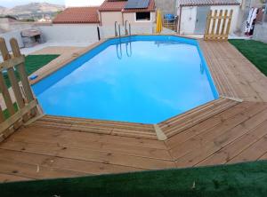 a swimming pool with a wooden deck and blue water at Casa Rinascita con Piscina Privata in Nulvi