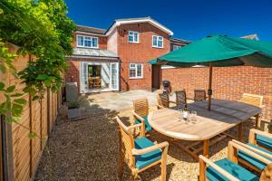 a patio with a wooden table with chairs and an umbrella at Little Tern in Brancaster