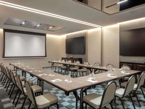 a conference room with tables and chairs and a screen at Hyde Hotel Dubai in Dubai +99 photos