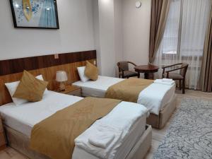 a hotel room with two beds and a table at FARIZ Hotel in Panjakent