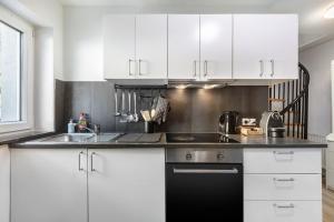 a kitchen with white cabinets and a black sink at Ferienwohnung Casa Marco 1 in Grenzach-Wyhlen