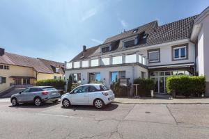 two cars parked in a parking lot in front of a house at Ferienwohnung Casa Marco 1 in Grenzach-Wyhlen