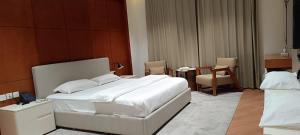 a bedroom with a white bed and a table and chairs at Al-TARABOT HOTEL in Muscat