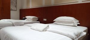 a room with three beds with white sheets and pillows at Al-TARABOT HOTEL in Muscat