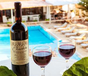 a bottle of wine next to two glasses of red wine at Stellina Hotel in Skiathos