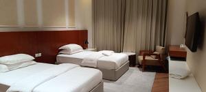 a hotel room with two beds and a flat screen tv at Al-TARABOT HOTEL in Muscat