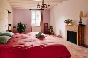 a bedroom with a red bed and a fireplace at L'Antre quatre- 4p- Piscine partagée- Site troglodytique in Fontaine-Milon +11 photos