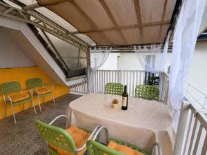 a room with a table with green chairs and a bottle of wine at Lila Central Apartman in Balatonlelle