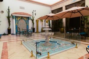 a fountain in a courtyard with tables and umbrellas at Hotel BouBabel in Nador