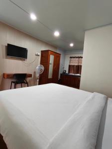 a bedroom with a white bed and a television at Spring Grove B&B in Jowai