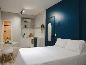 a bedroom with a white bed and a blue wall at Apê Metrô Paraíso in São Paulo