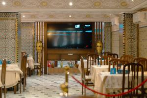 a dining room with tables and a large screen television at Hotel BouBabel in Nador