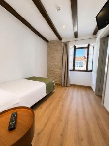 a bedroom with a bed and a table and a television at Hotel Restaurante Plati in Villarcayo