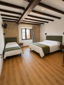 two beds in a large room with wooden floors at Hotel Restaurante Plati in Villarcayo
