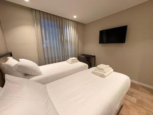 a hotel room with two beds and a flat screen tv at Origen Patagonia Hotel in Puerto San Julián