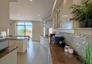 a large kitchen with white cabinets and plants in it at Apartment 24 in Durban
