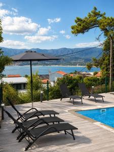 a group of chairs and an umbrella next to a swimming pool at Carimar, a mirada da ría in Boiro