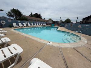a large swimming pool with white chairs at Atlantic Motel in Point Pleasant Beach