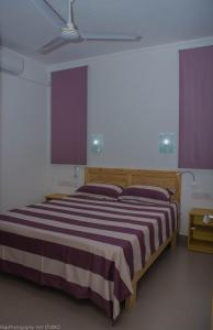 1 dormitorio con 1 cama grande y cortinas moradas en Villa Alexis - Location de vacances à Trou aux Biches, en Trou aux Biches