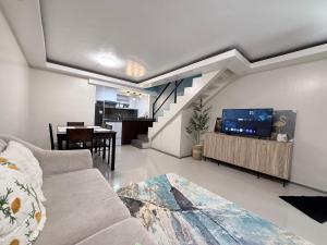 a living room with a couch and a tv and a staircase at Jabs cabin 2 in Angeles +4 photos