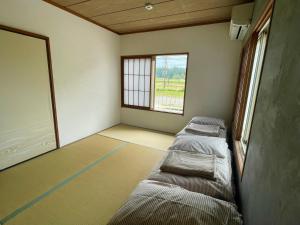 a room with three beds in it with a window at ゲストハウス紗乃葉 - Suzunoha in Bōchū