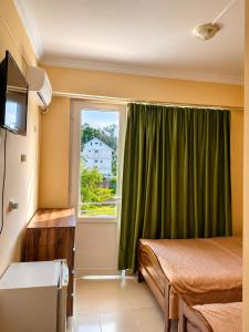 a room with a bed and a window with green curtains at Mziuri Guest House in Ureki