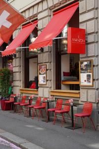 a row of red chairs and tables outside of a restaurant at Hotel St.Gotthard in Zurich