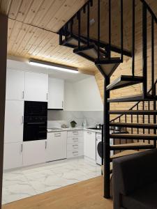 a kitchen with white cabinets and a black spiral staircase at CottageNEO in Charnali +13 photos