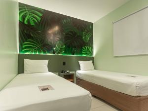 two beds in a room with a painting on the wall at ibis Styles Belém do Pará in Belém +145 photos