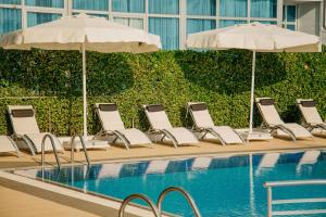 a row of chairs and umbrellas next to a pool at Era Palace Gonio in Kvariati
