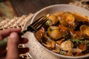 a person is eating a bowl of food with a fork at Pousada Vila do Mar in Caraíva