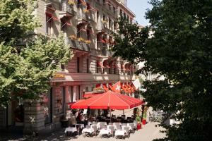 a building with tables and chairs and a red umbrella at Hotel St.Gotthard in Zurich