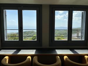 a bench in a room with three windows at TERPOU StoneHouse & Suites in Volos