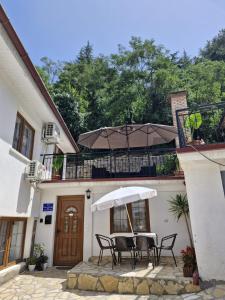a table with chairs and an umbrella in front of a building at Villa Elena in Ohrid