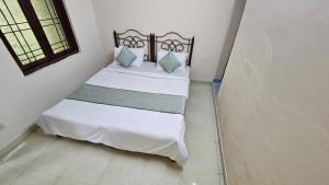 a bedroom with a bed with white sheets and blue pillows at Value Stays By Amisha Palace in Jaipur